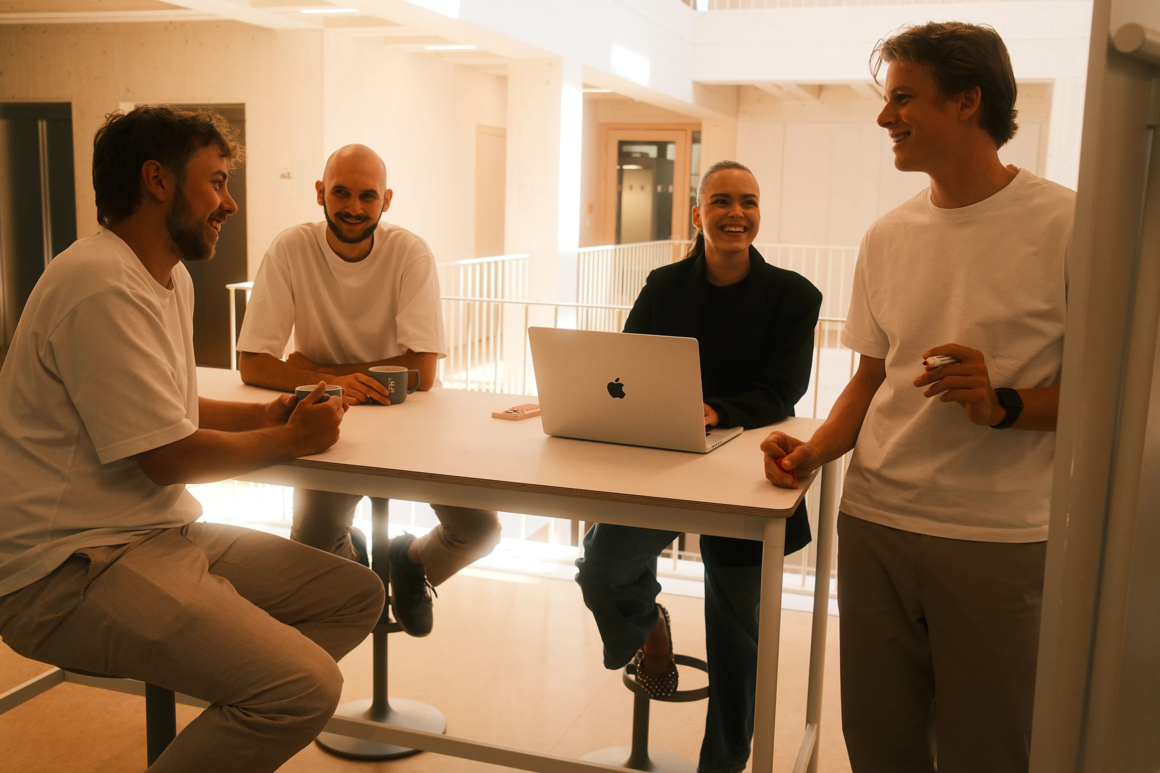 Das Team von P&A Development lacht gemeinsam bei einer Besprechung am Stehtisch im Büro Heilbronn