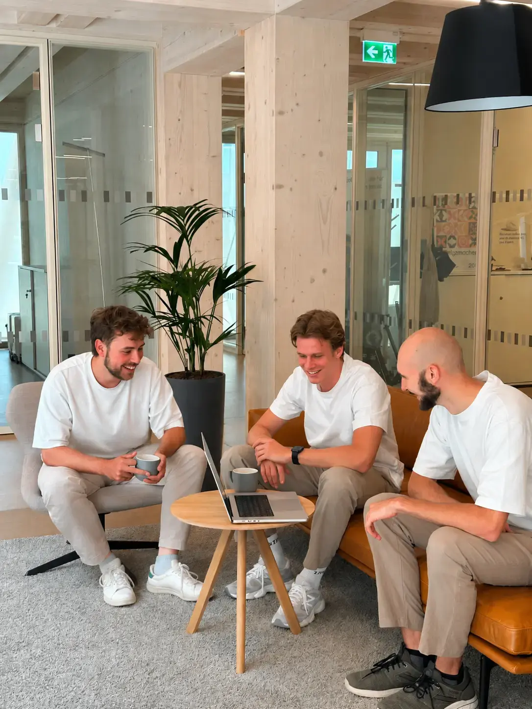 Drei Entwickler von P&A Development besprechen ein Projekt entspannt auf dem Sofa